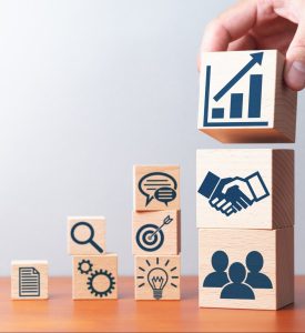 Planning of business strategy. Business development and success. Building wood blocks with icons on table.