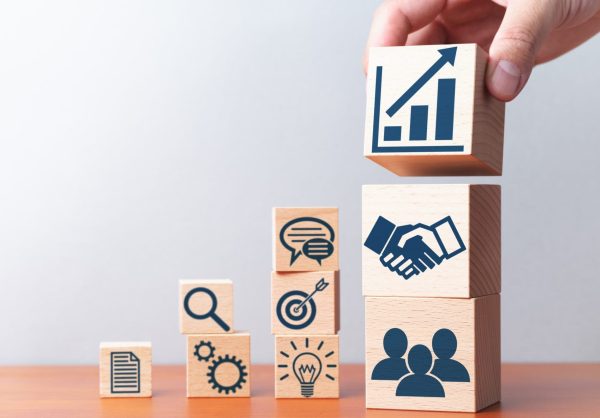 Planning of business strategy. Business development and success. Building wood blocks with icons on table.