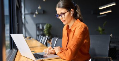 Indian entrepreneur manager businesswoman using pc for communication, learning at workplace. Focused latin hispanic young business woman working on laptop computer sitting at office workplace desk