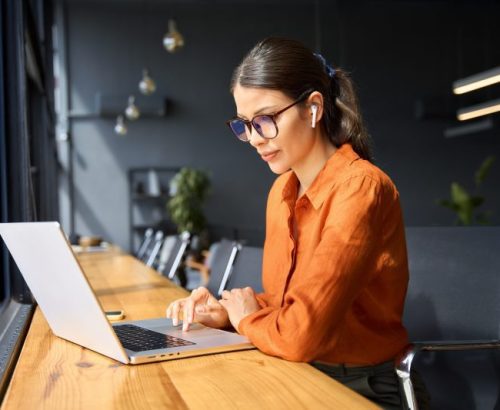 Indian entrepreneur manager businesswoman using pc for communication, learning at workplace. Focused latin hispanic young business woman working on laptop computer sitting at office workplace desk