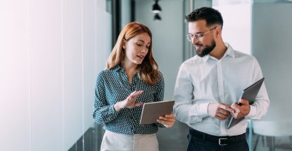 Making decision on the move Shot of two coworkers having a discussion in modern office. Businessman and businesswoman in meeting using digital tablet and discussing business strategy. Confident business people working together in the office. Creative business persons discussing new project and sharing ideas in the workplace.