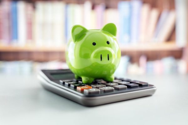 Green piggy bank with calculator concept for savings, banking and business account Green piggy bank on calculator concept for saving money, accounting, banking and business account